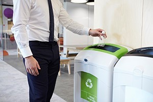 A worker in an office recycling his water bottle and being more sustainable